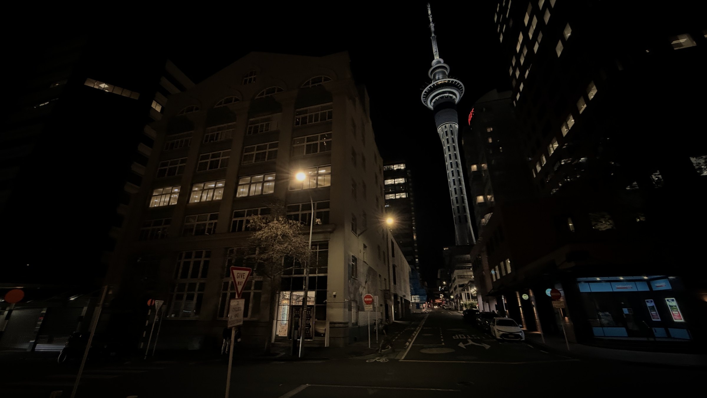 Cathedral House on Wyndham Street at night, with the Sky Tower behind